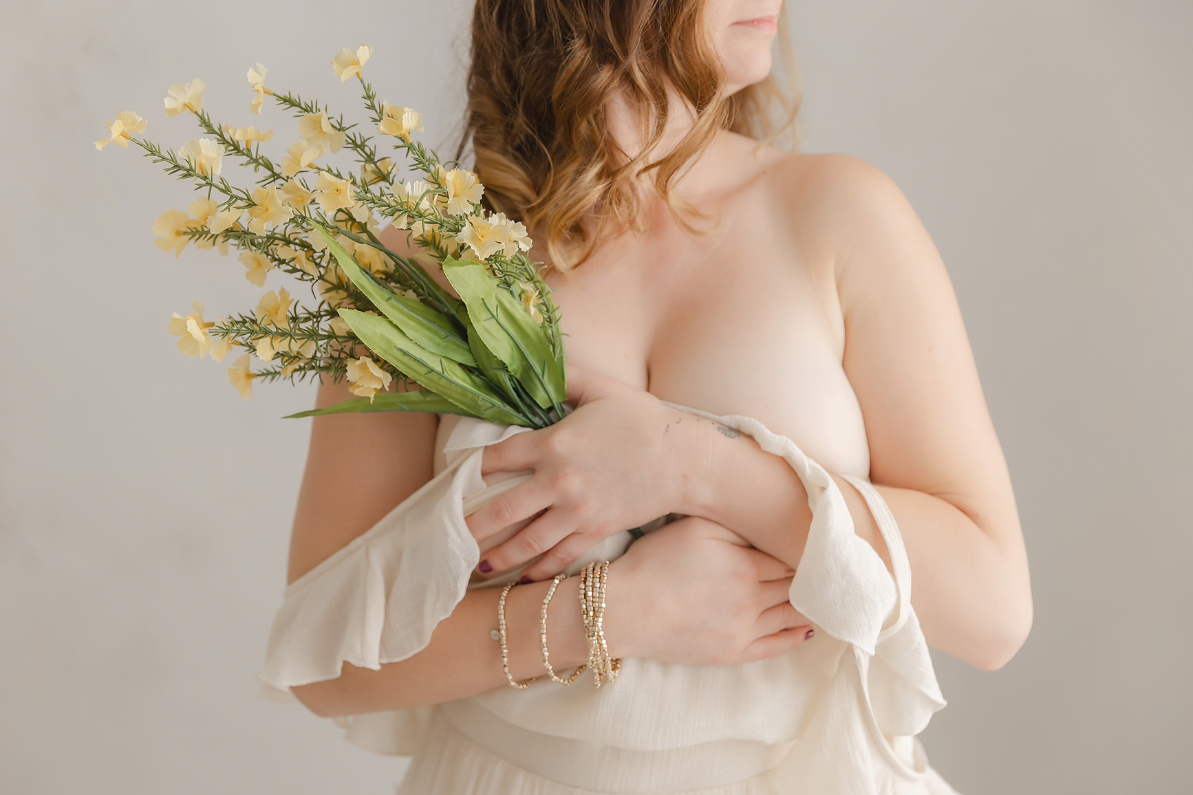 woman holding a spray of yellow flowers to her chest