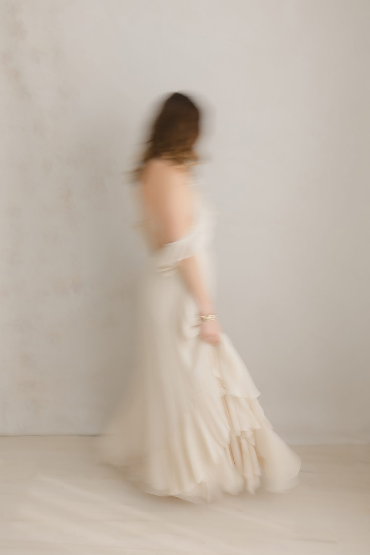 blurry photo of a woman in a beige dress walking through the frame